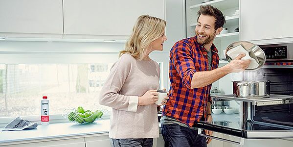 Una coppia sta cucinando felicemente in cucina. Anche dopo aver cucinato ci si può rilassare. Grazie ai prodotti di pulizia proWIN la pulizia è un gioco da ragazzi.